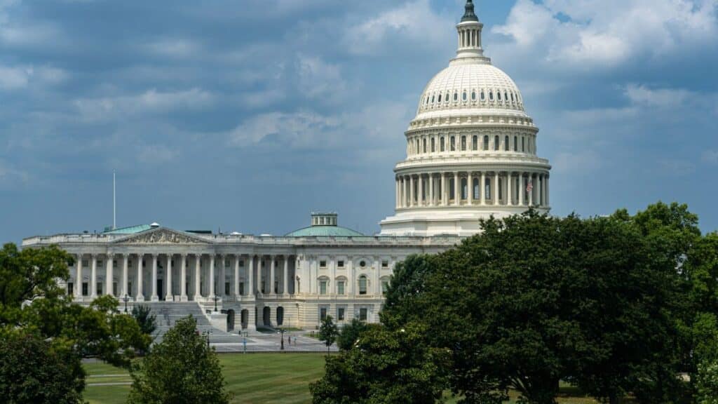 Iconic view of the United States Capitol Building surrounded by lush greenery on a sunny day.