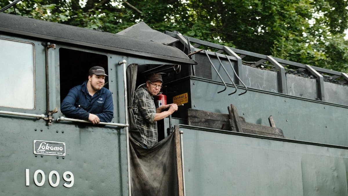 Two men on a vintage train in Lahti, showcasing historic Finnish railway.