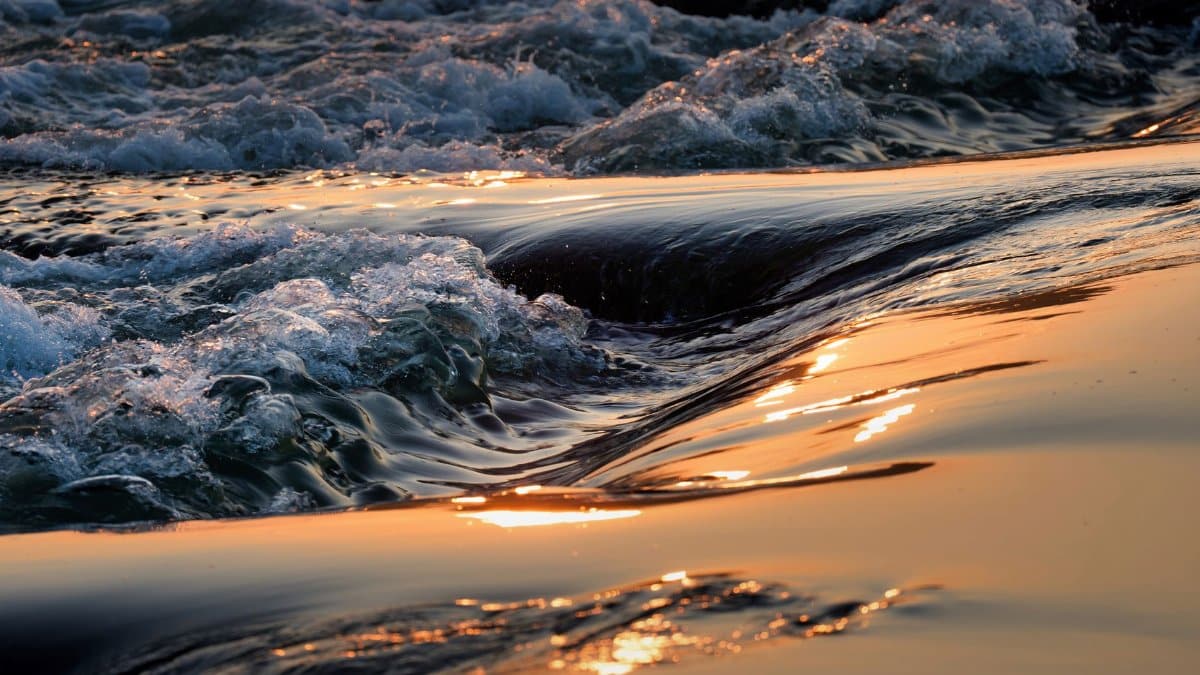 Golden sunrise reflecting on waves in a tranquil seascape scene.