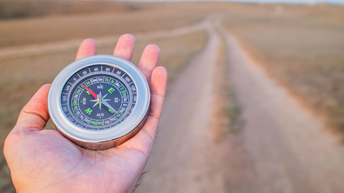 Hand holding a compass guiding along a dusty path outdoors. Perfect for travel and exploration themes.