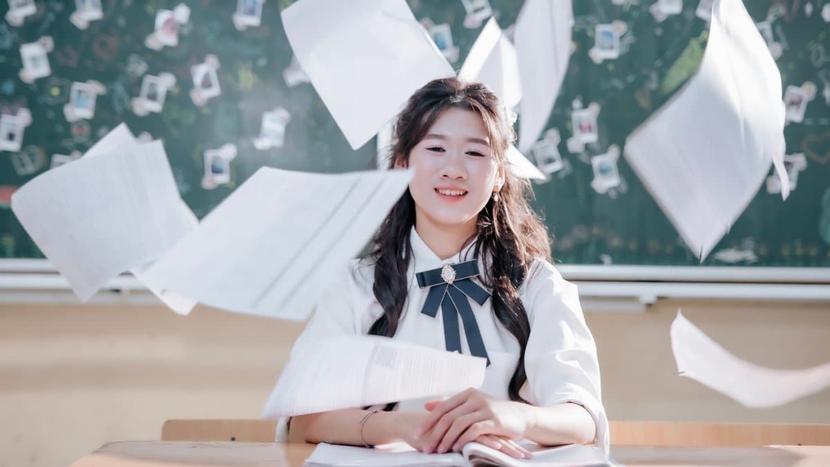 Happy student throws papers in classroom in celebration of school year ending. Cheerful academic success.