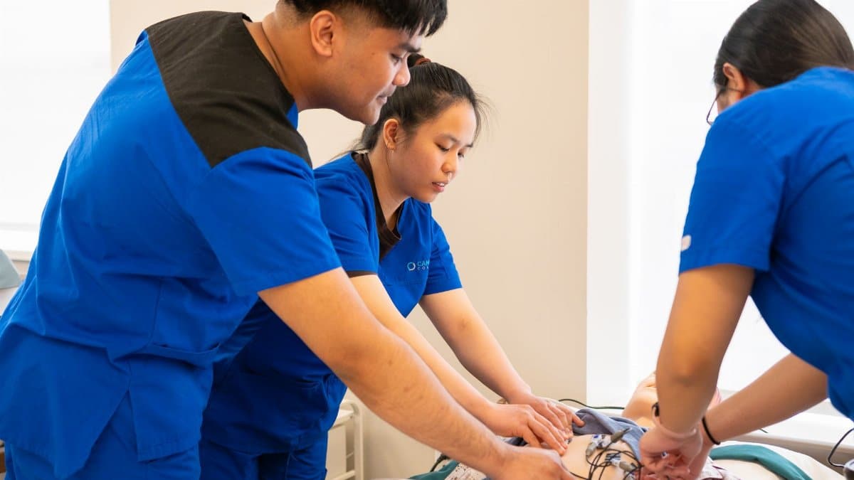 Group of nursing students conducting a medical procedure in a training room.