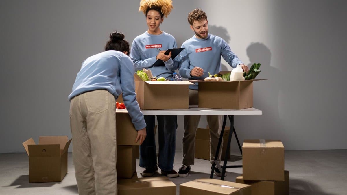 Three volunteers organizing food donations into boxes, showing teamwork and community support.
