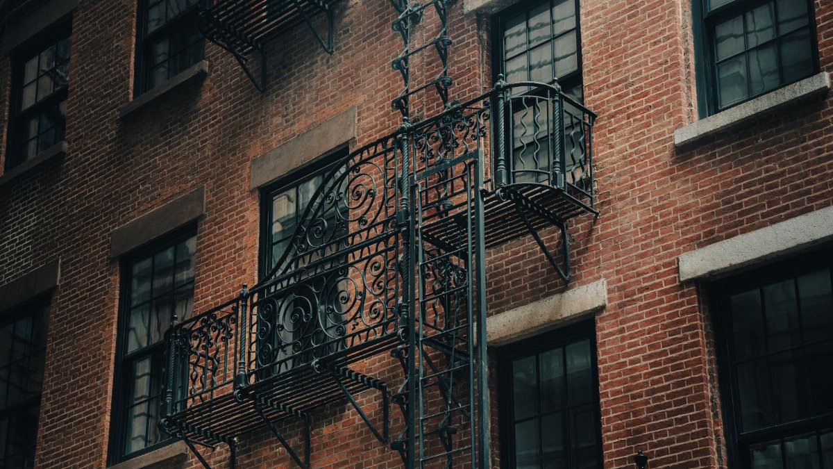 Close-up of a classic New York City fire escape on a red brick building facade.