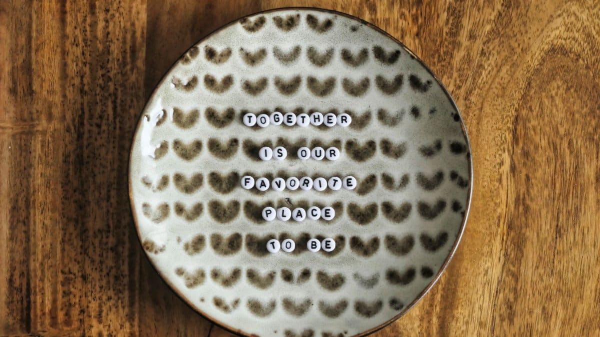 A decorative plate on a wood table with the message 'Together is our favorite place to be.' Perfect for love or relationship themes.