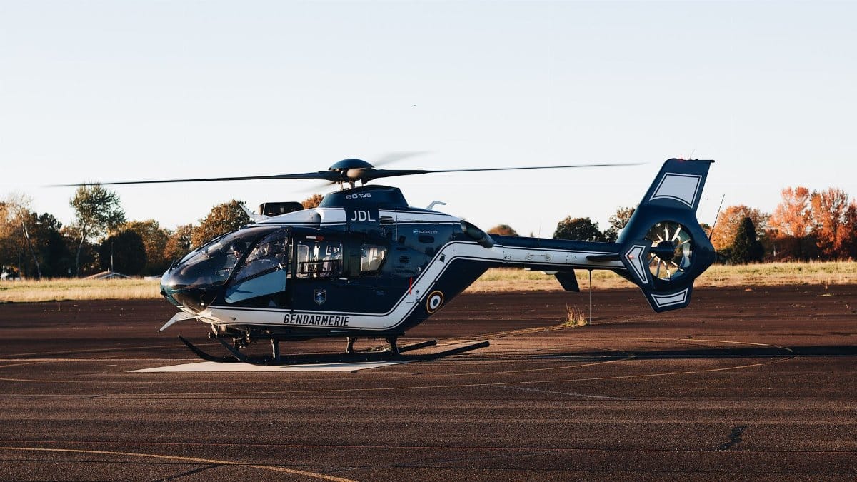 A Gendarmerie helicopter stationed on an airport runway during sunset, showcasing law enforcement aviation.
