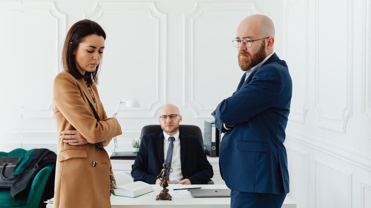 A couple in corporate attire seeks mediation during a business disagreement in an office setting.