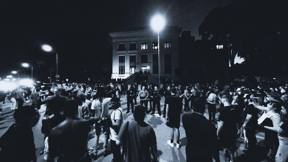A monochrome scene of a large crowd gathering for a nighttime protest in Chattanooga, TN.