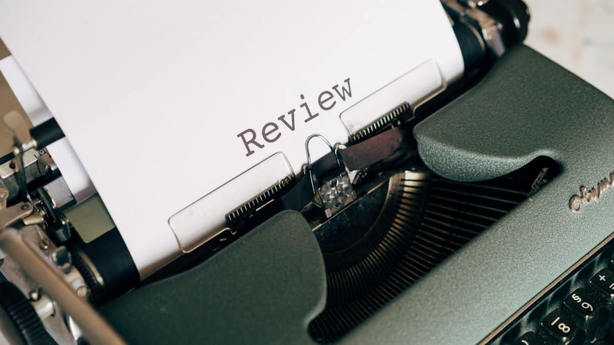 Close-up of an antique typewriter printing the word 'Review' on white paper.