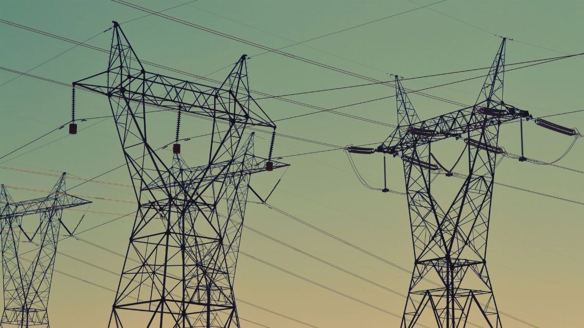 Silhouette of high voltage power lines against a twilight sky, illustrating energy infrastructure.