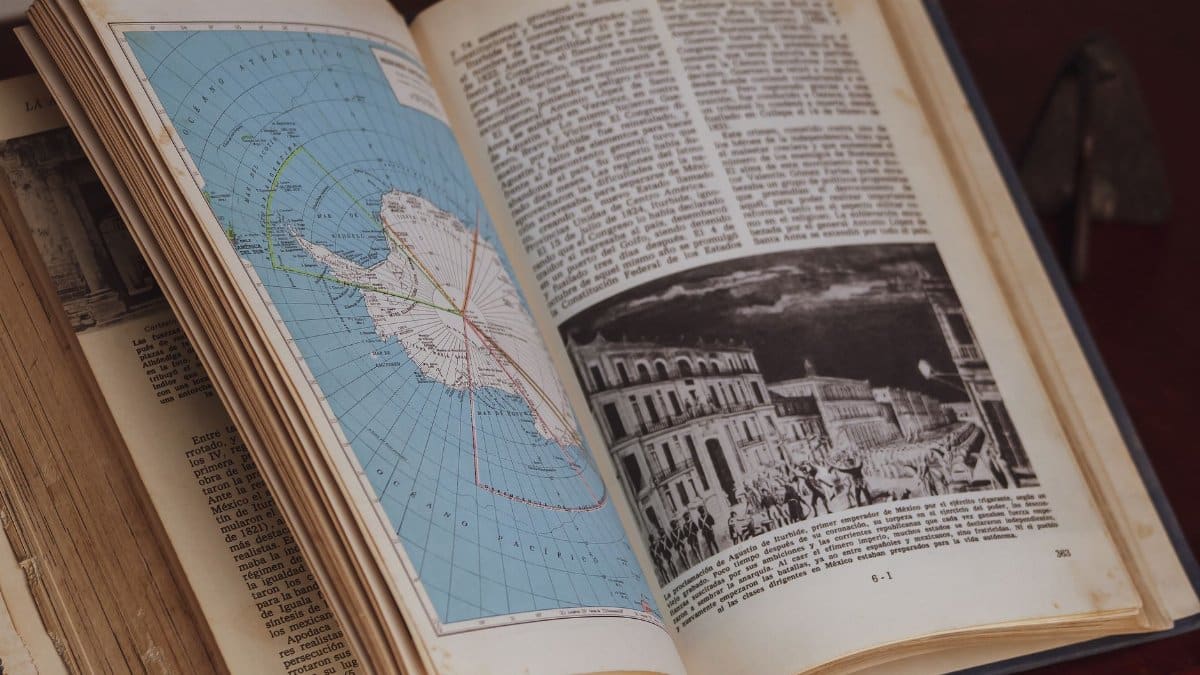 Detailed close-up of an open history book showing a vintage map and illustration.