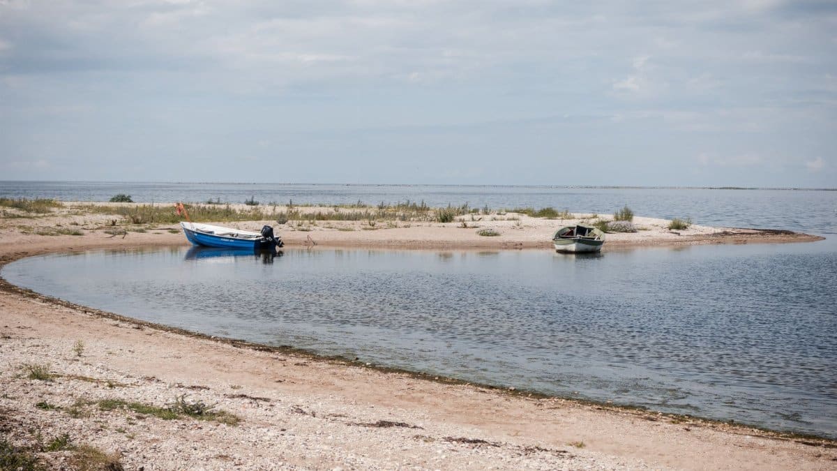 Peaceful beach scene with boats and calm water, perfect for relaxation and travel themes.