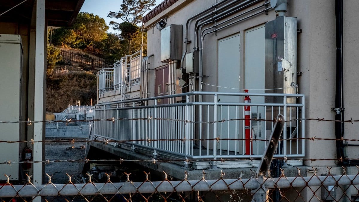 Outdoor industrial scene showcasing a building with metal railings and barbed wire fence at sunset.