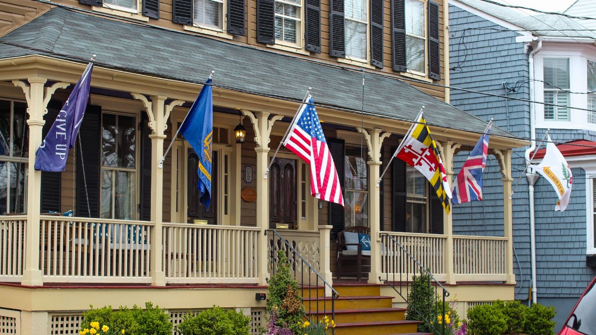 Historic house in Annapolis, Maryland, displaying various flags on a charming porch.