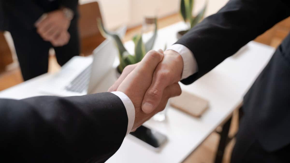 Close-up of a handshake between two professionals in a business setting, symbolizing agreement.