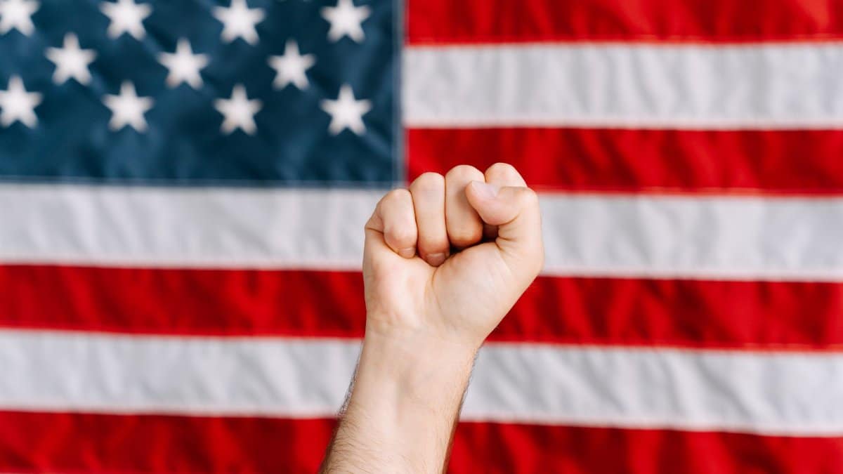 A raised fist in front of an American flag, symbolizing patriotism and activism.