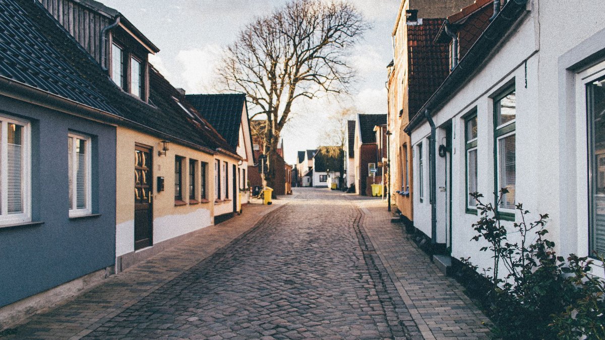 Picturesque cobblestone street lined with quaint houses under a clear spring sky.