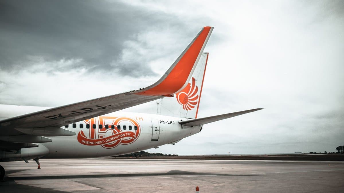 Close-up view of a Boeing 737 wing on the runway with a cloudy sky background.