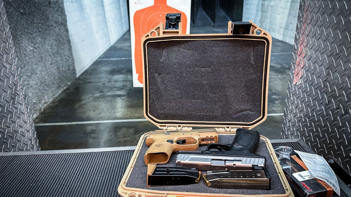 Open handgun case with firearm and accessories at an indoor shooting range.