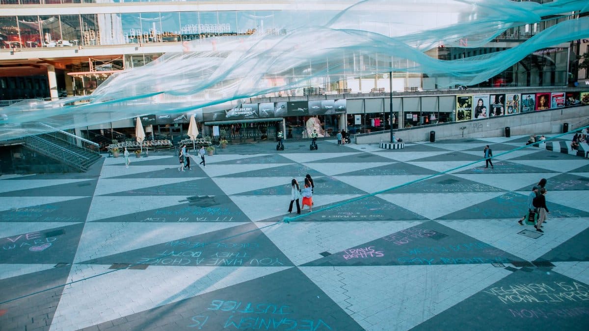 A bustling urban square with colorful art installations and people enjoying the scene.