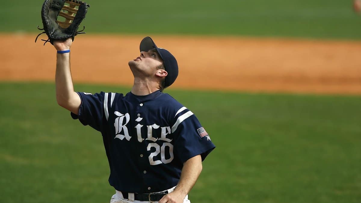 Baseball player in blue jersey catching a ball on a grassy field during a game.
