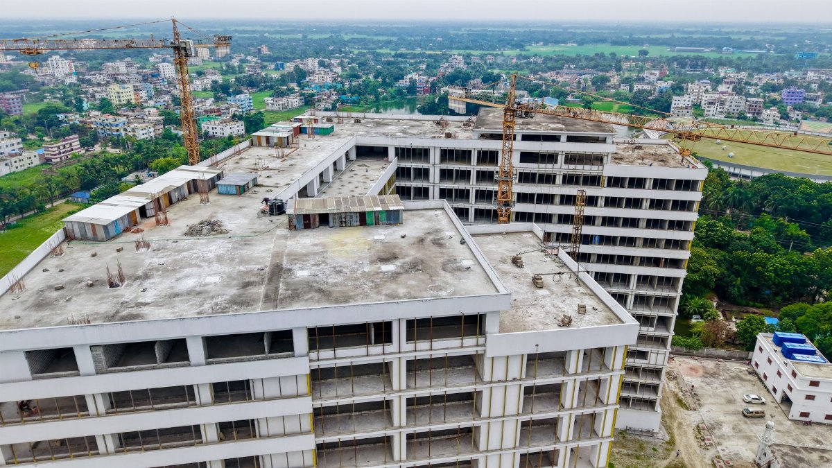 High-rise building under construction in an urban setting with prominent cranes.