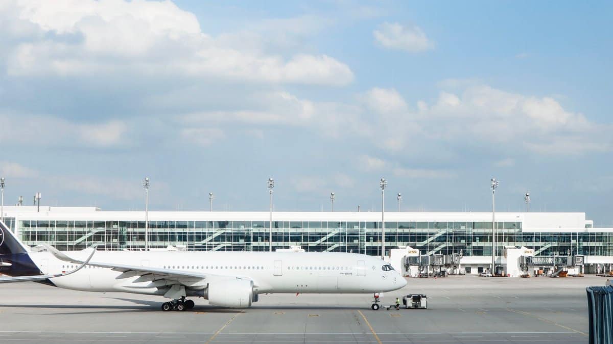 Widebody aircraft parked at an airport gate during clear day with terminal building visible.