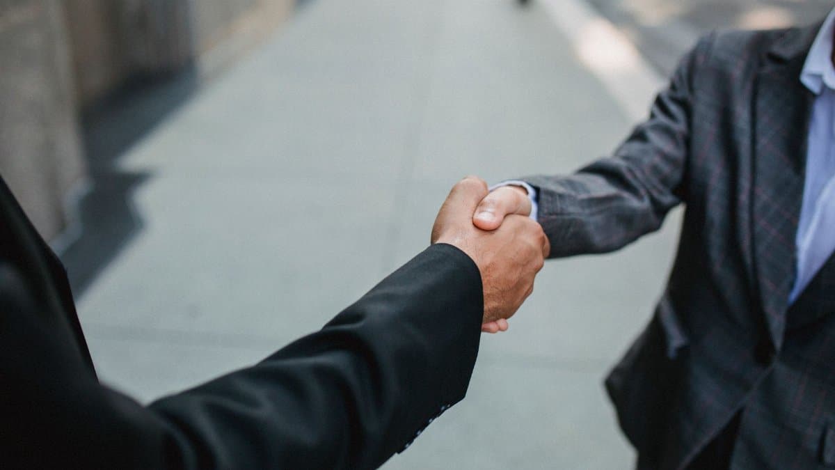 Close-up of two businessmen shaking hands outside, symbolizing partnership and agreement.