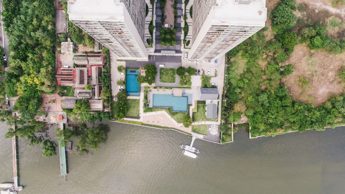 Drone shot of high-rise buildings along a lush, green waterfront.
