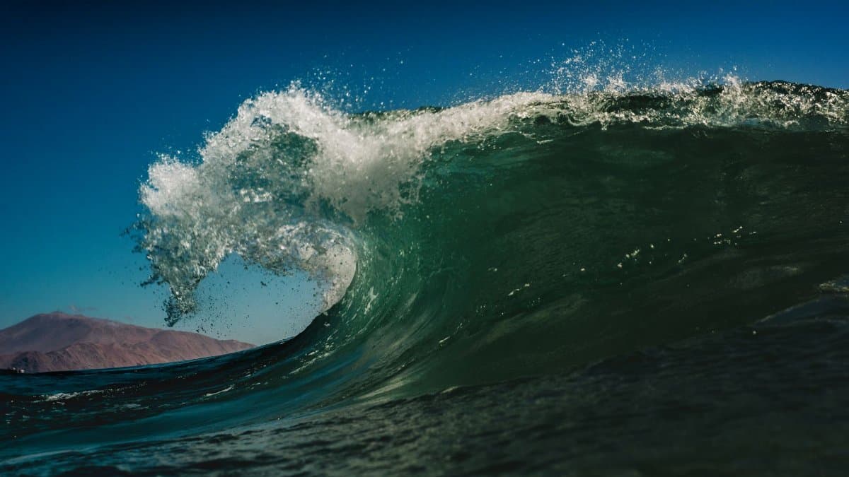 Experience the power and beauty of a towering ocean wave captured in Chile on a sunny day.