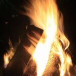 A burning bonfire set against the dark night sky creates a warm glow.