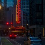 A lively street view of the illuminated Paramount Theatre in Boston at dusk, showcasing urban architecture.