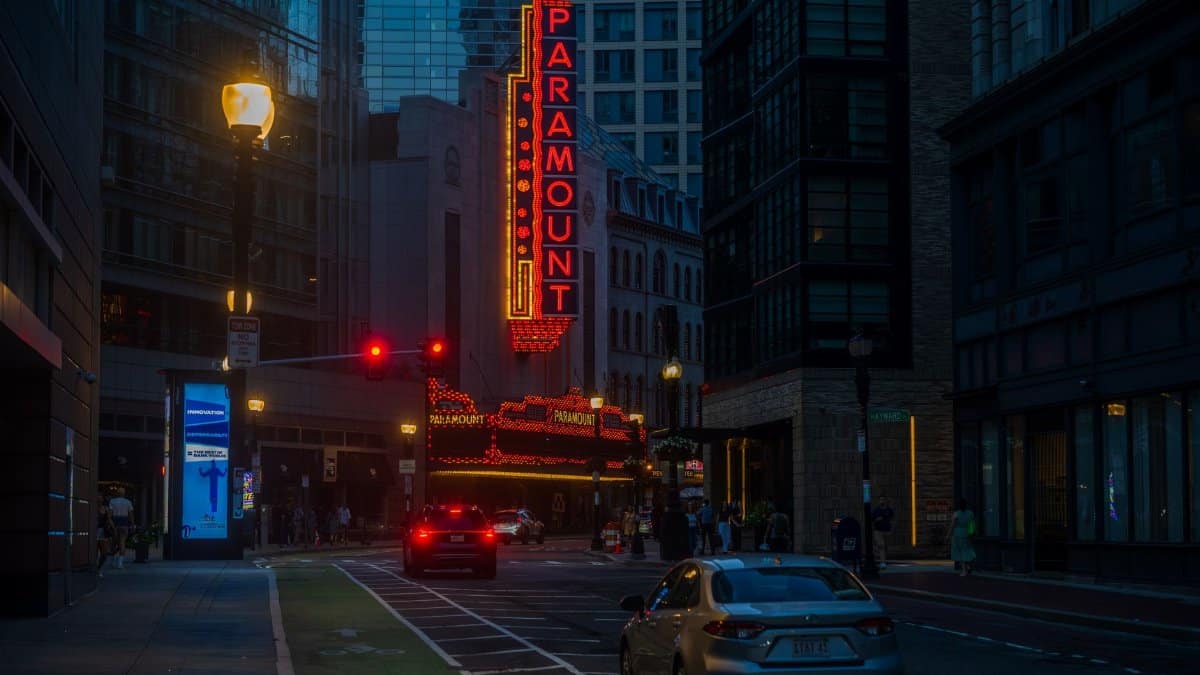 A lively street view of the illuminated Paramount Theatre in Boston at dusk, showcasing urban architecture.