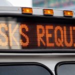 Close-up of a bus display sign showing 'Masks Required' for COVID-19 public transportation safety.