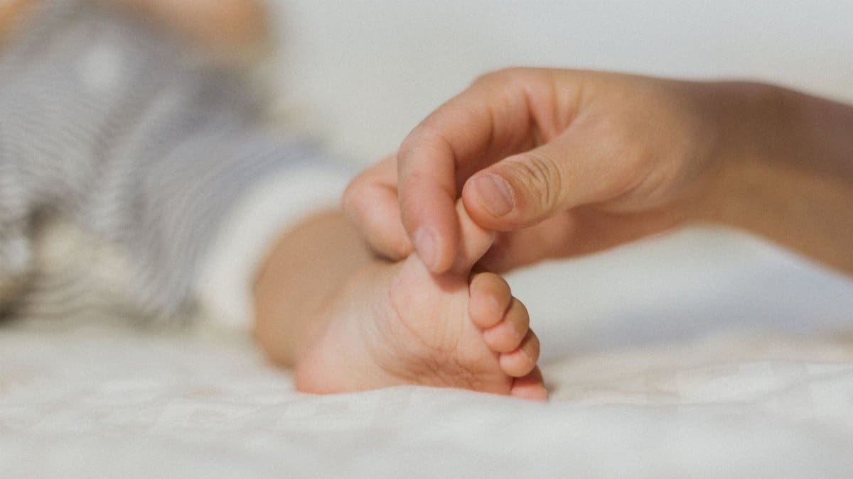 Close-up of a parent's hand gently holding a baby's foot, symbolizing love and care.