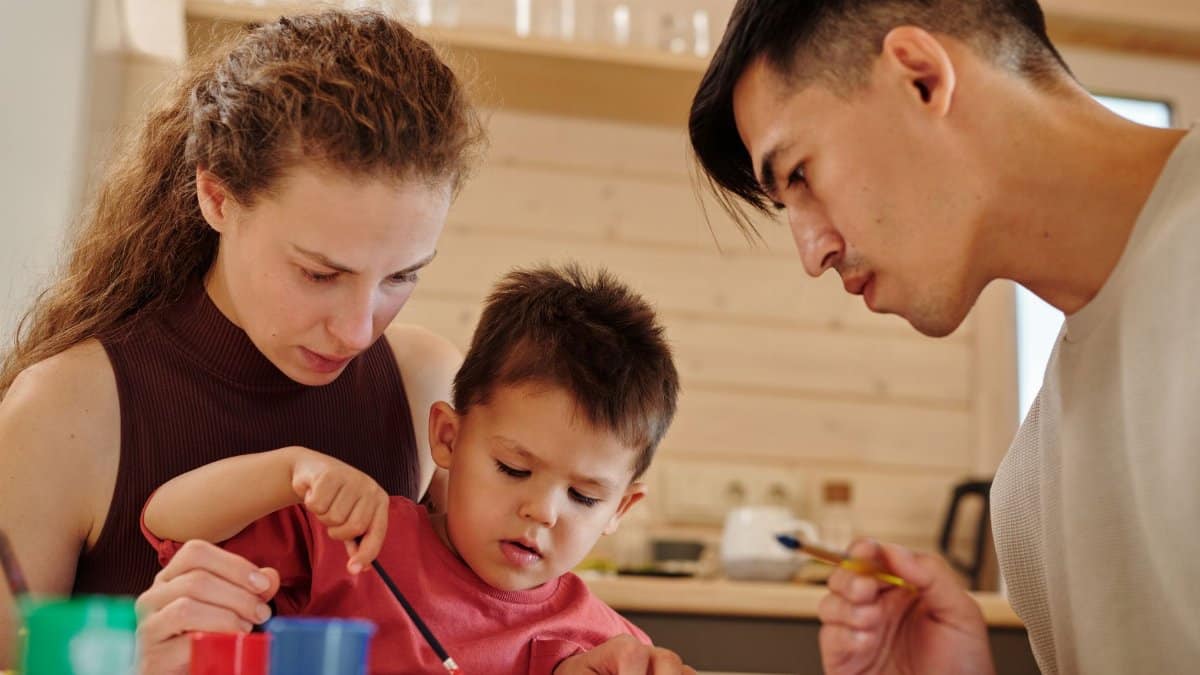 A family spends quality time painting together indoors, fostering creativity and connection.