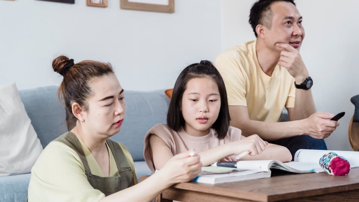 A family helping their daughter with homework in the living room, promoting togetherness.