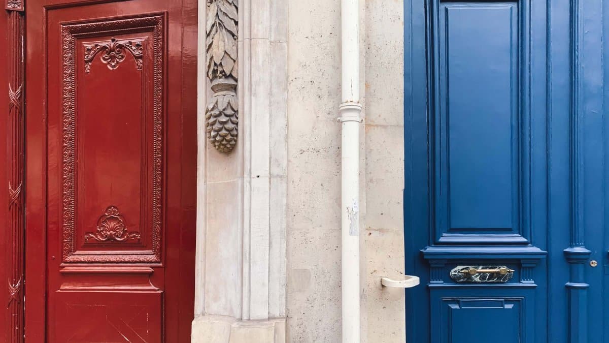 Elegant red and blue doors in Paris with intricate carvings showcasing classic architectural design.