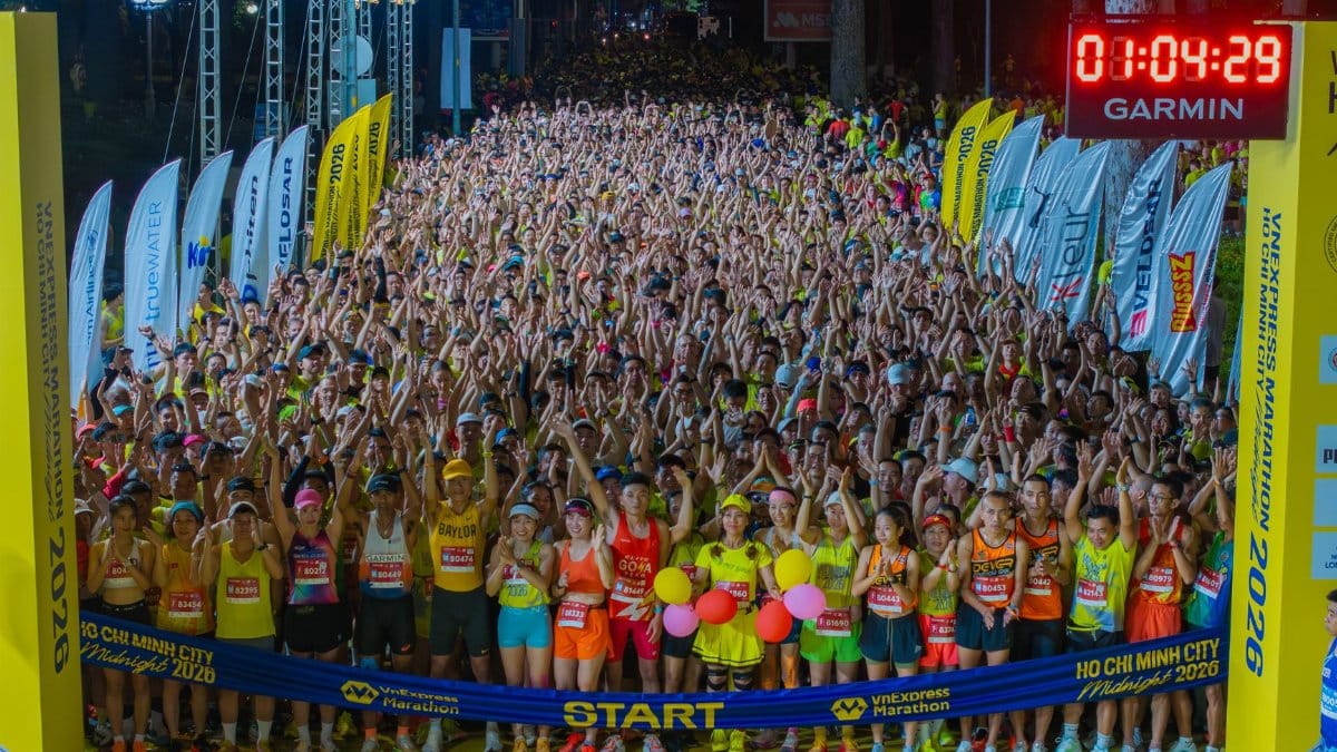 Crowds gather at the start of a midnight marathon in Ho Chi Minh City under bright lights.