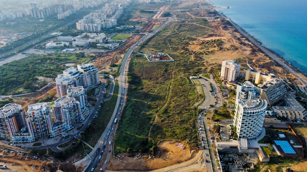 Breathtaking aerial view of urban development along a picturesque coastline, showcasing city and natural beauty.
