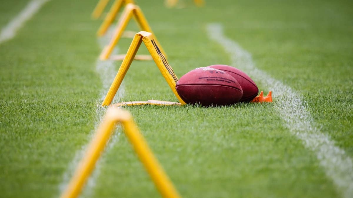 Close-up of an American football on a sports field with yellow training equipment.