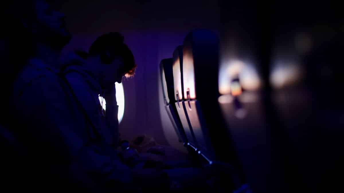 Passengers resting in a dimly lit airplane with purple ambient lighting, showcasing a peaceful travel experience.