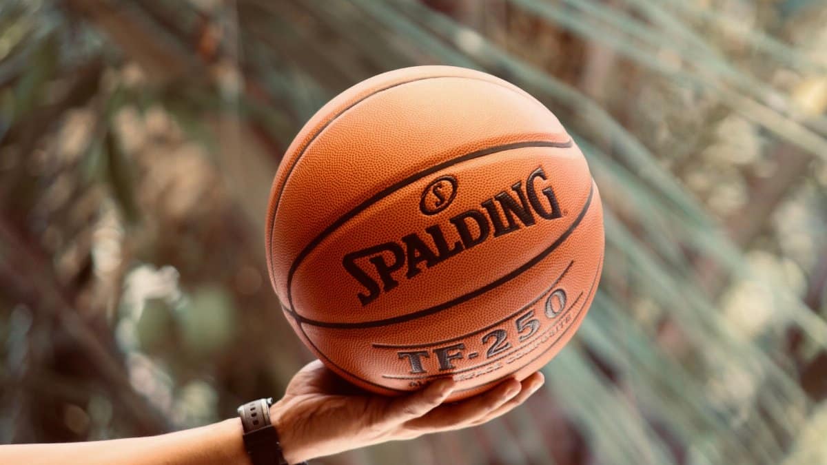 A close-up shot of a hand holding a Spalding basketball outdoors, showcasing sports enthusiasm.