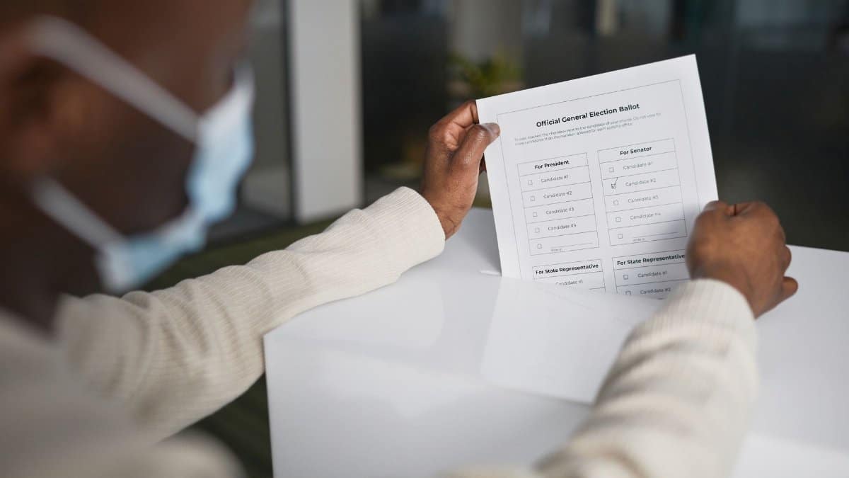 African American man wearing face mask casting a vote with official ballot