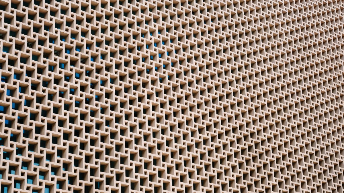 A detailed view of a geometric concrete wall with repetitive patterns and open spaces.