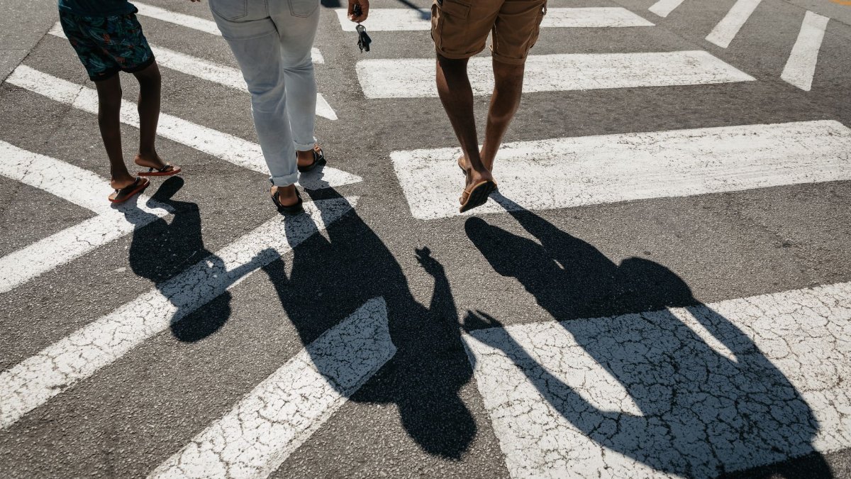 A family walking across a zebra crossing, representing safety and care.