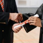 Close-up of a graduate receiving diploma during a graduation ceremony handshake.