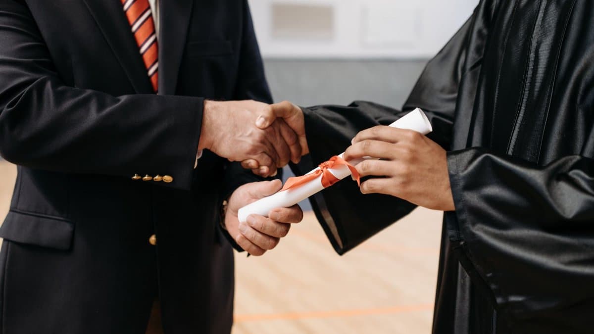 Close-up of a graduate receiving diploma during a graduation ceremony handshake.