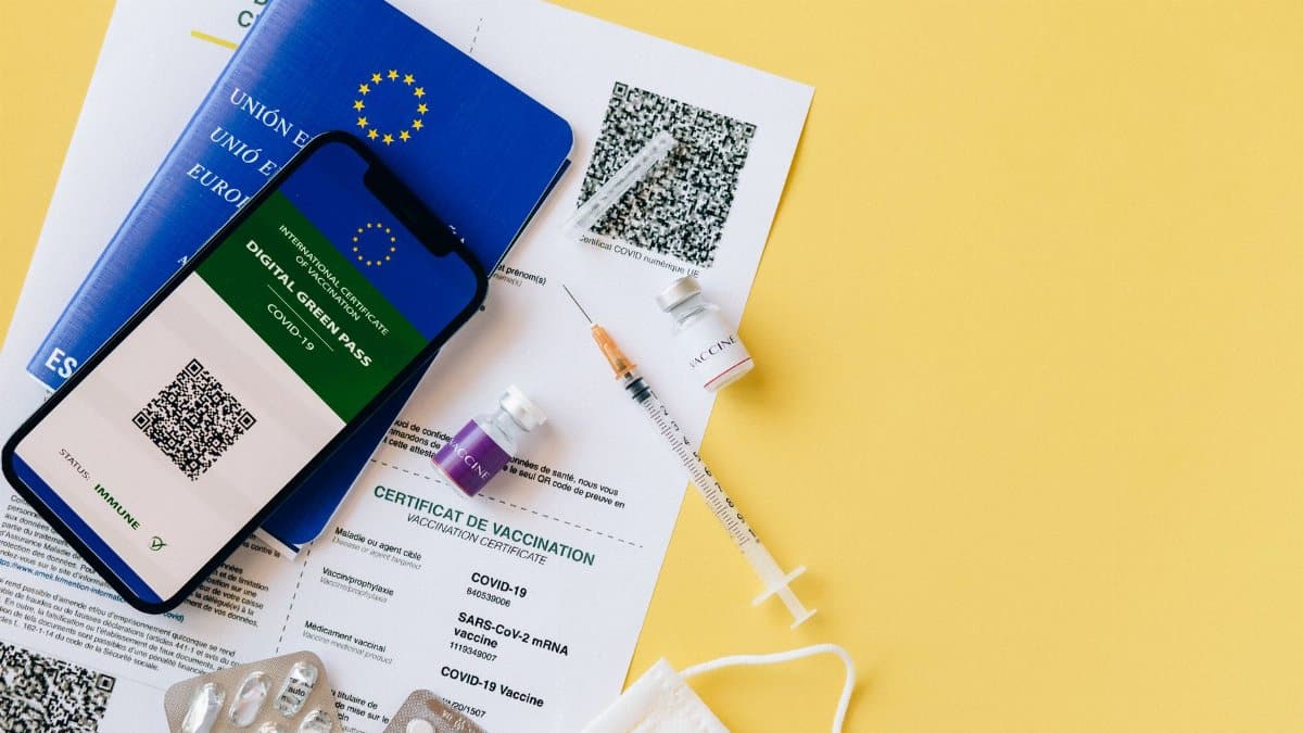 Digital vaccine passport and COVID-19 vaccination items including syringes and masks on a yellow background.