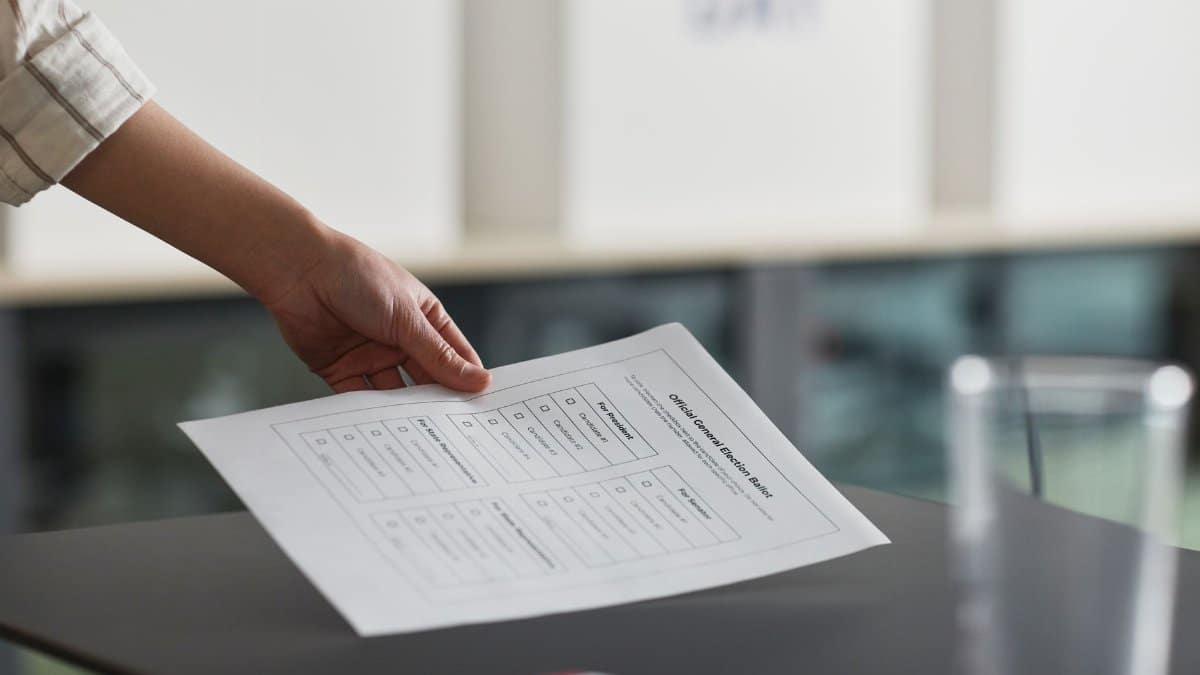 Close-up of a hand holding a ballot paper indoors, symbolizing democracy and civil rights.